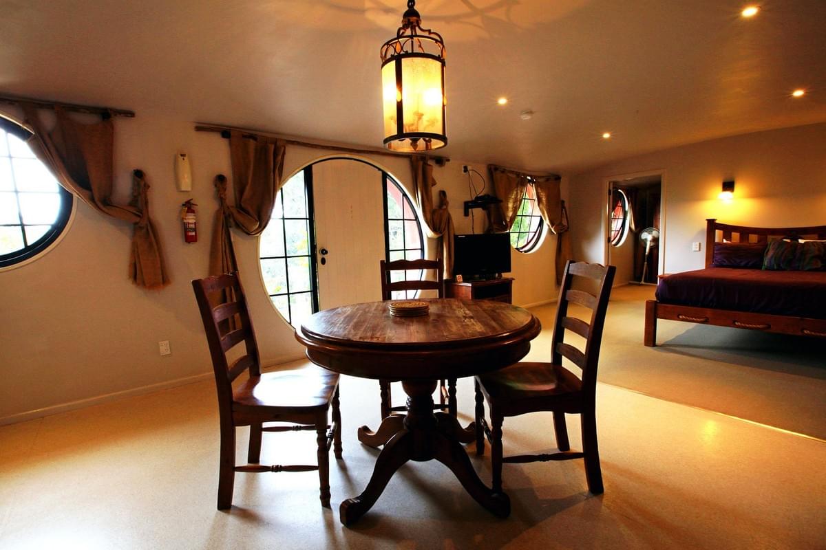 Inside a Hobbit unit at Woodlyn Park, with a round window, dining table and bed